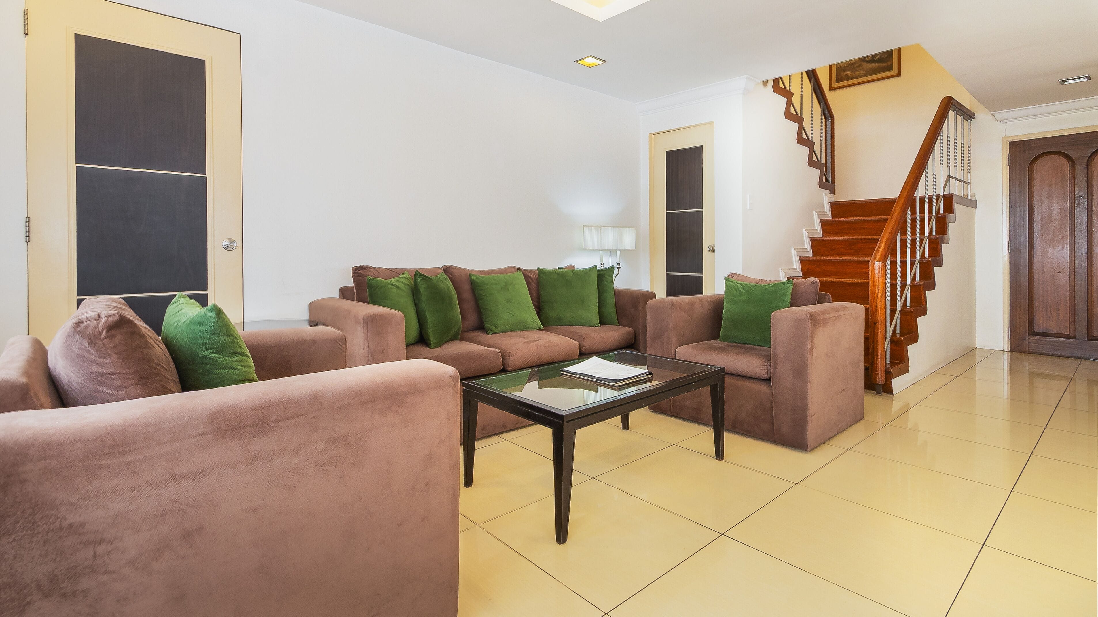 A living room with a sofa set, a coffee table, and a staircase.