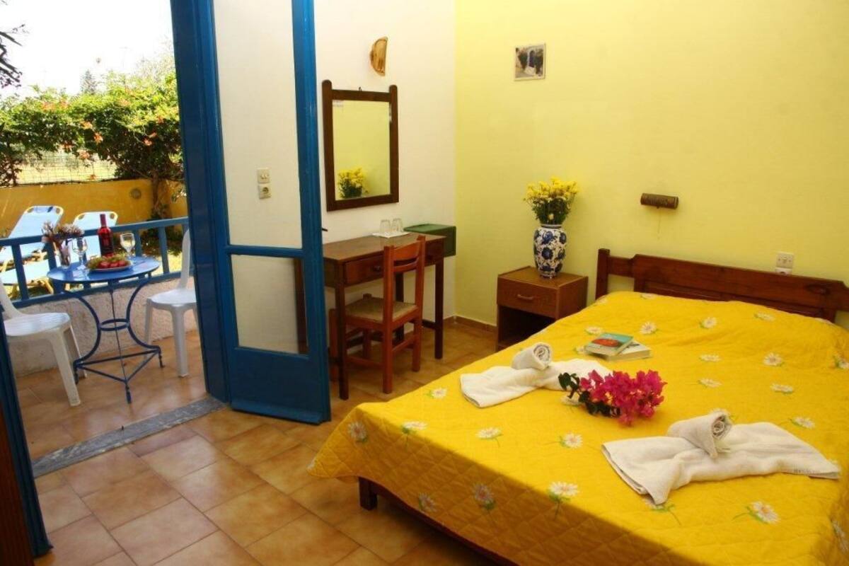 A hotel room with a bed, a desk, a chair, and a small table.