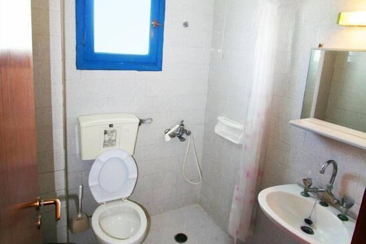 A small, basic bathroom with a toilet, a shower, and a sink.