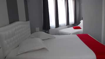 Una habitación de hotel con dos camas, una colcha roja y un ventanal con cortinas.