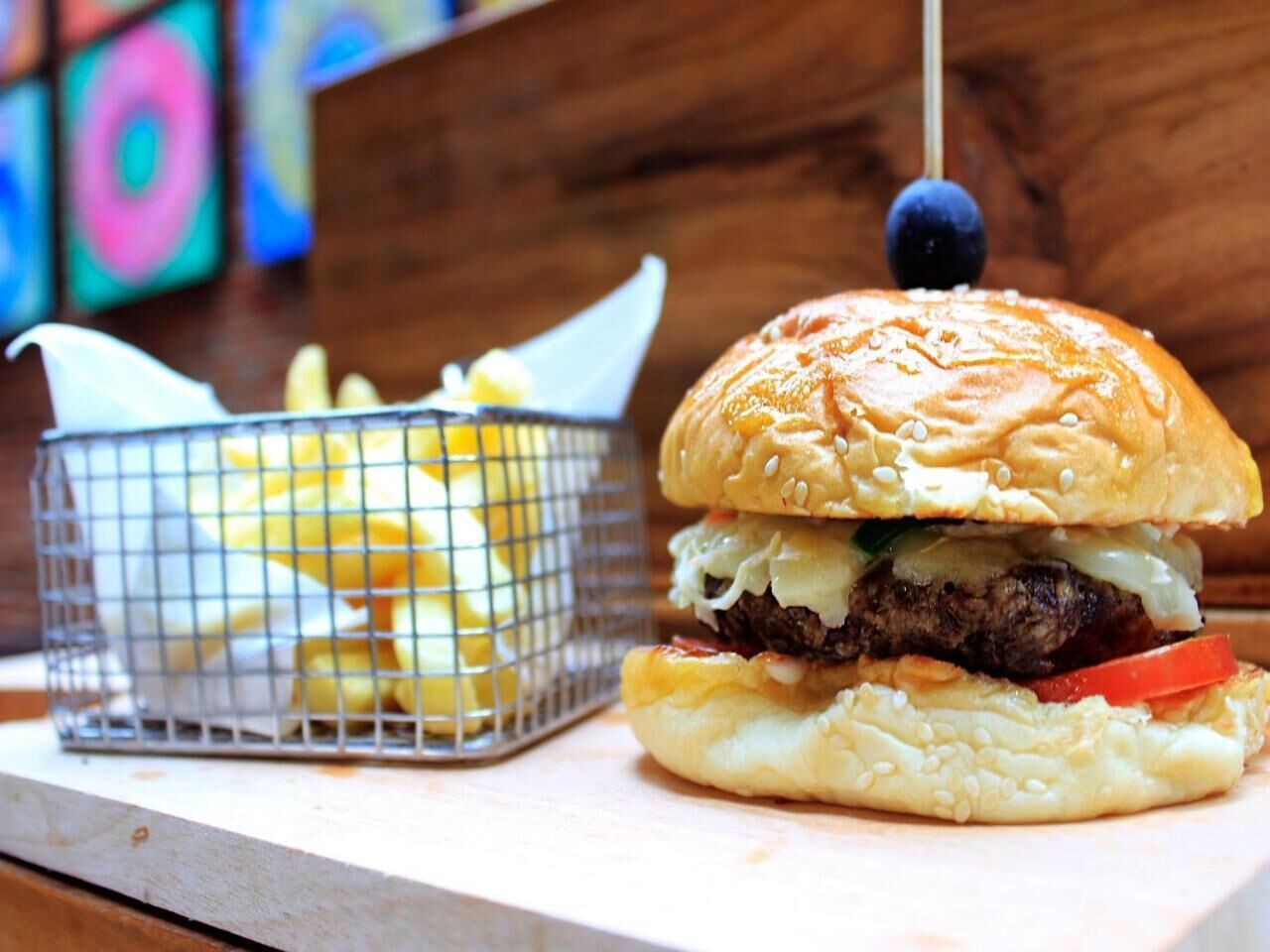 A burger with lettuce, cheese, and a beef patty, accompanied by a basket of fries.
