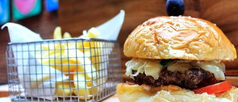 A burger with lettuce, cheese, and a beef patty, accompanied by a basket of fries.