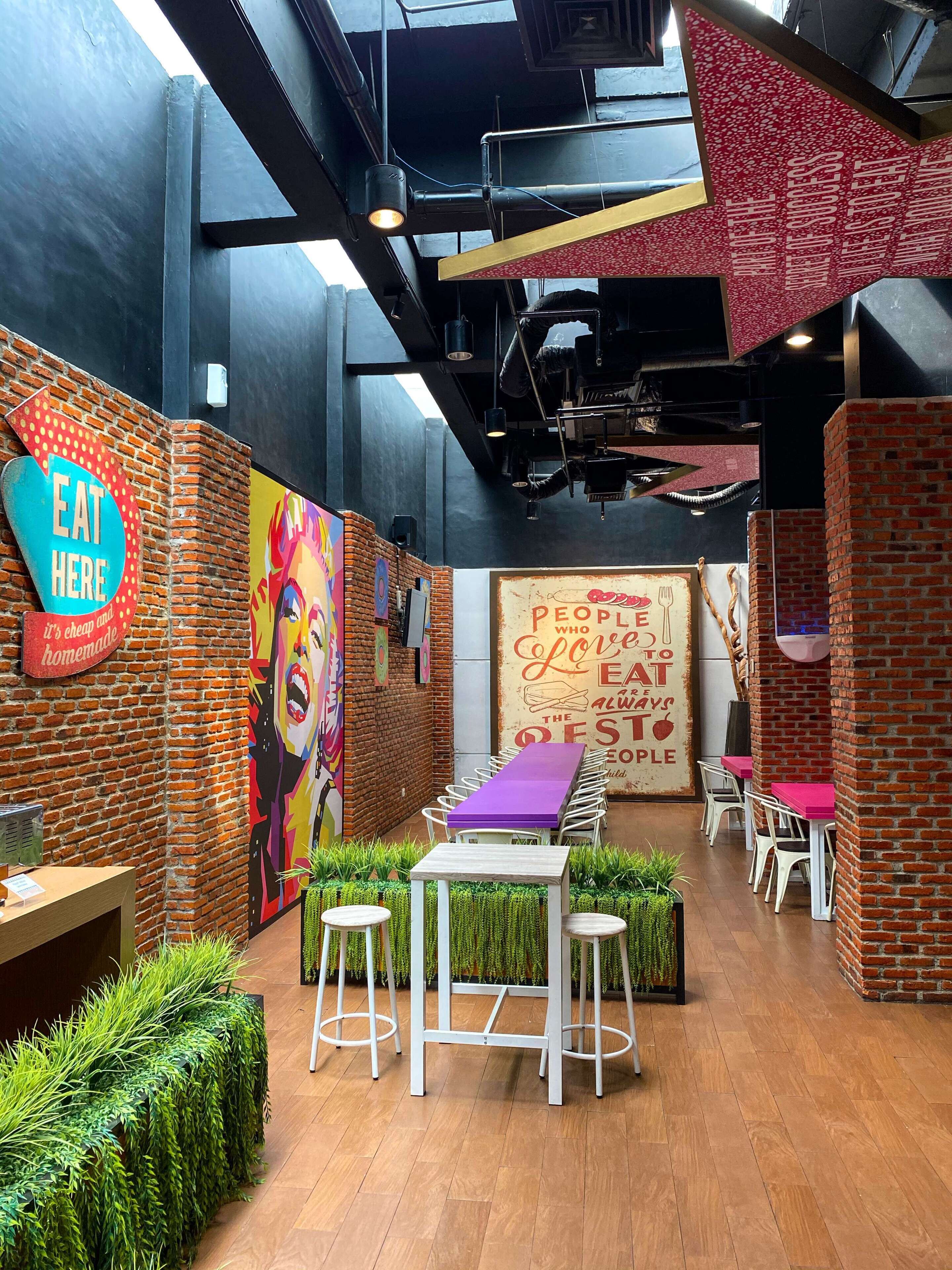 A modern dining area with brick walls, colorful murals, and a mix of white and purple furniture.