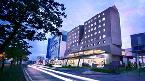 Un hotel moderno con un diseño arquitectónico único, que destaca por su entrada imponente y fachada bien iluminada.