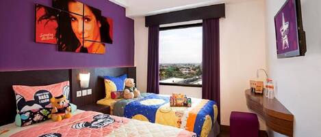 A hotel room with two beds, a large window with a view, a wall-mounted TV, and a small wooden shelf with toiletries.