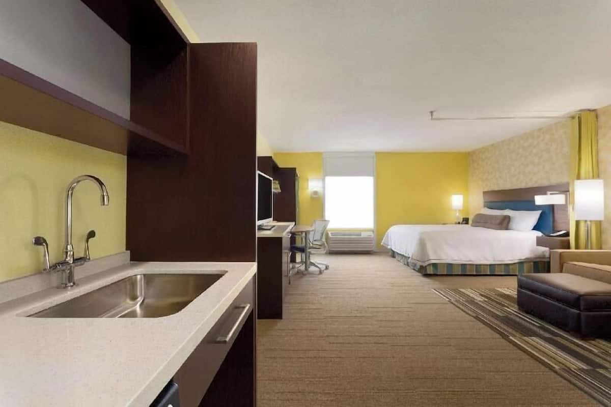 Une chambre d’hôtel équipée d’une kitchenette, d’un lit, d’un bureau et d’une salle de bain.
