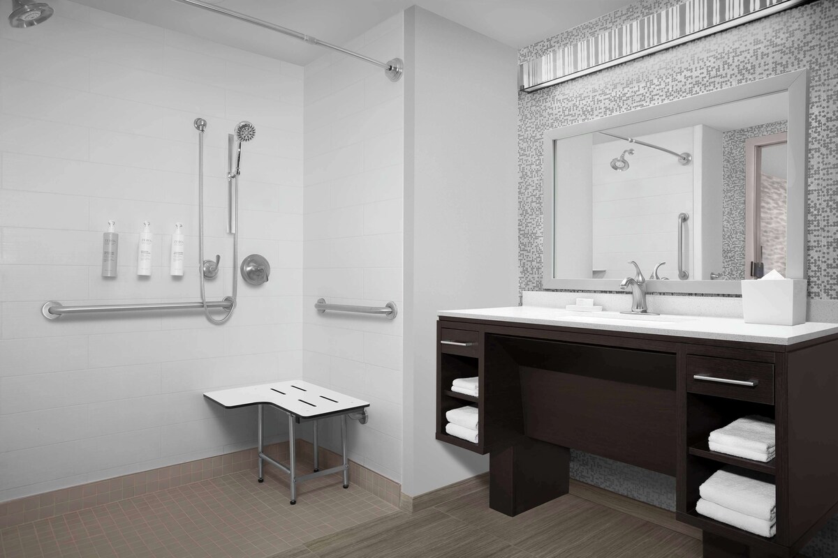 A modern bathroom with a shower, vanity, and a mirror.