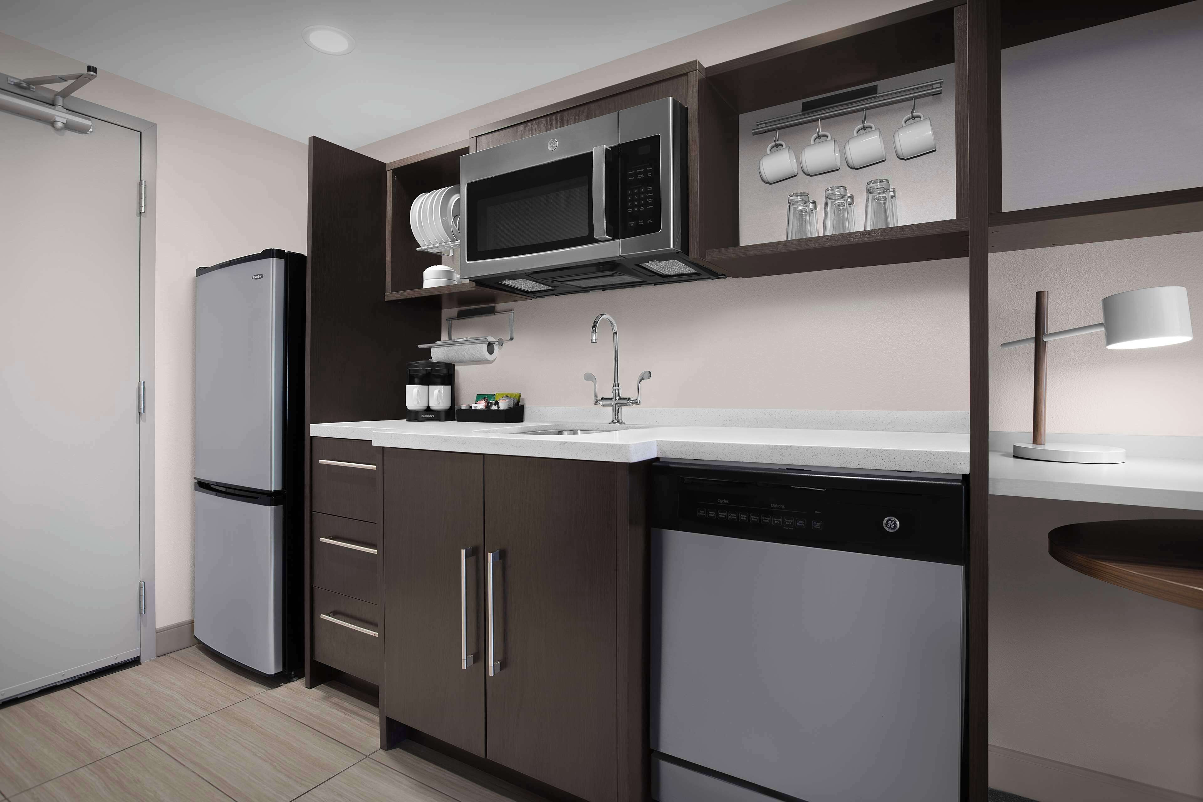 Une cuisine moderne équipée d’appareils électroménagers en acier inoxydable, d’un lave-vaisselle et d’un four à micro-ondes.