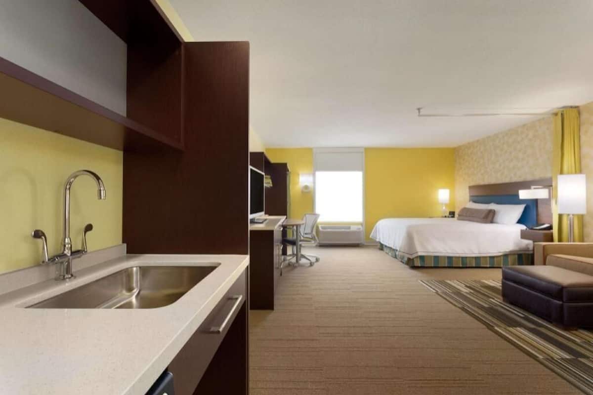 Une chambre d’hôtel équipée d’une kitchenette, d’un lit, d’un bureau et d’une salle de bain.