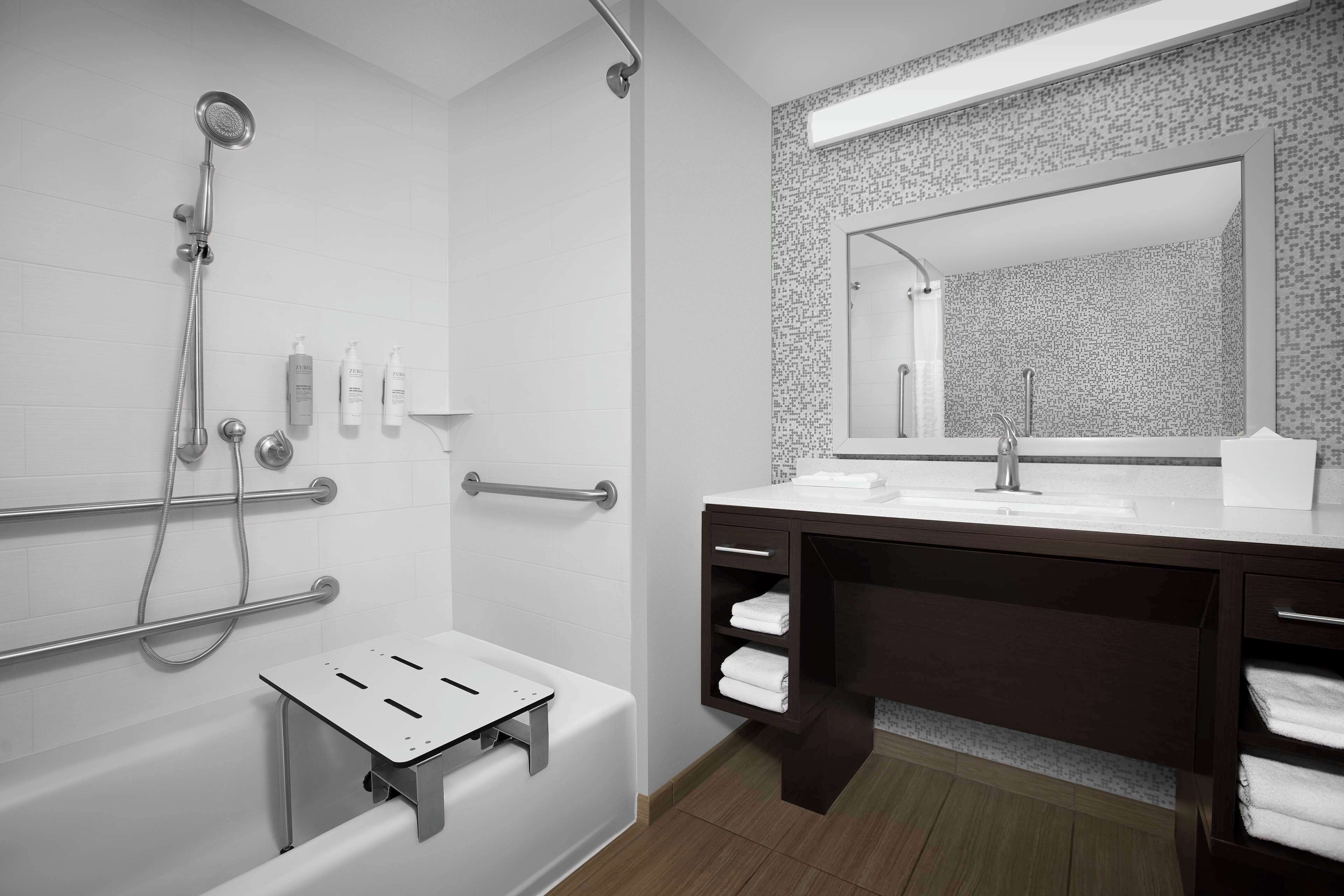 Een moderne badkamer met een badkuip, douche en een wastafel met een grote spiegel.