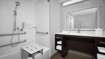 Een moderne badkamer met een badkuip, douche en een wastafel met een grote spiegel.