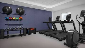 A gym with treadmills, a rowing machine, and kettlebells.