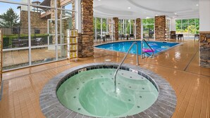 Ein Whirlpool mit Steinsäulen, ein Schwimmbecken und eine Terrasse mit Sitzgelegenheiten im Freien.