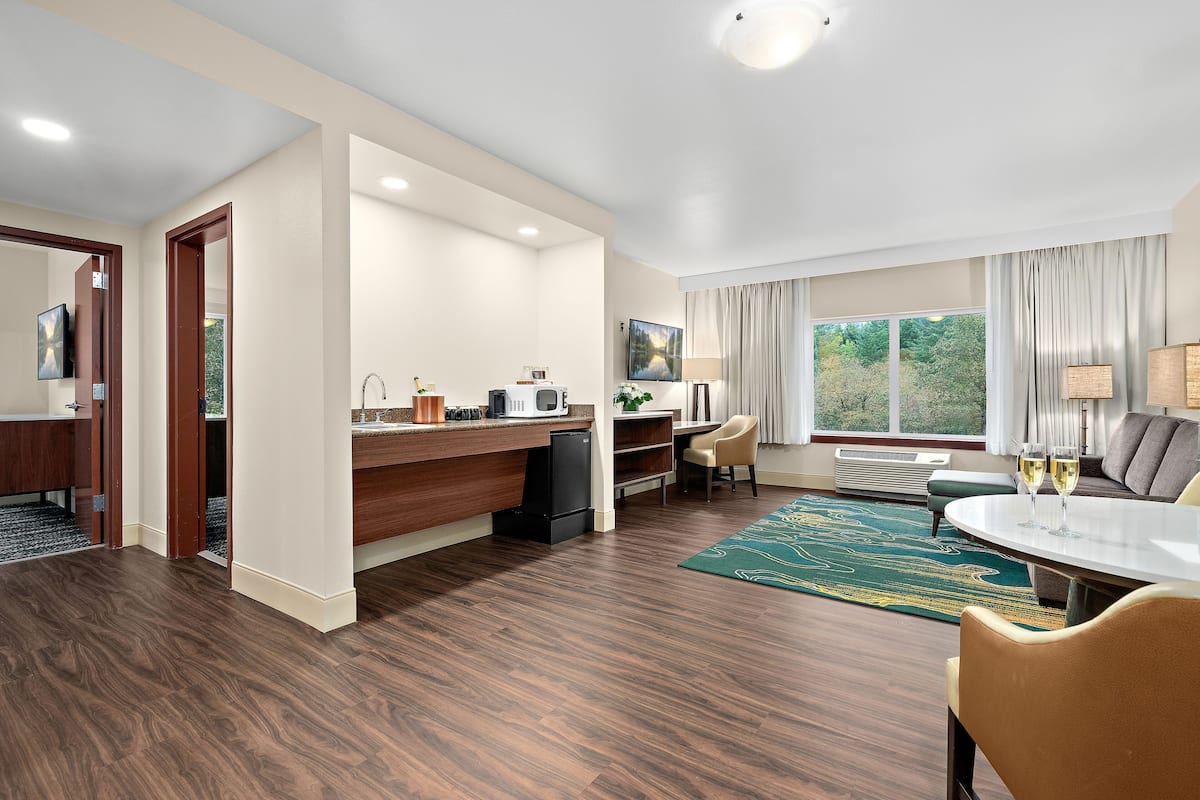 Una habitación de hotel moderna con cocina, una mesa de comedor y una zona de estar con vistas al exterior.