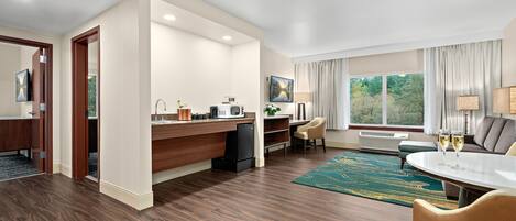 Una habitación de hotel moderna con cocina, una mesa de comedor y una zona de estar con vistas al exterior.
