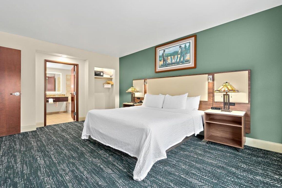 Una habitación de hotel con una cama grande, una mesita de noche, una lámpara y un cuadro en la pared.