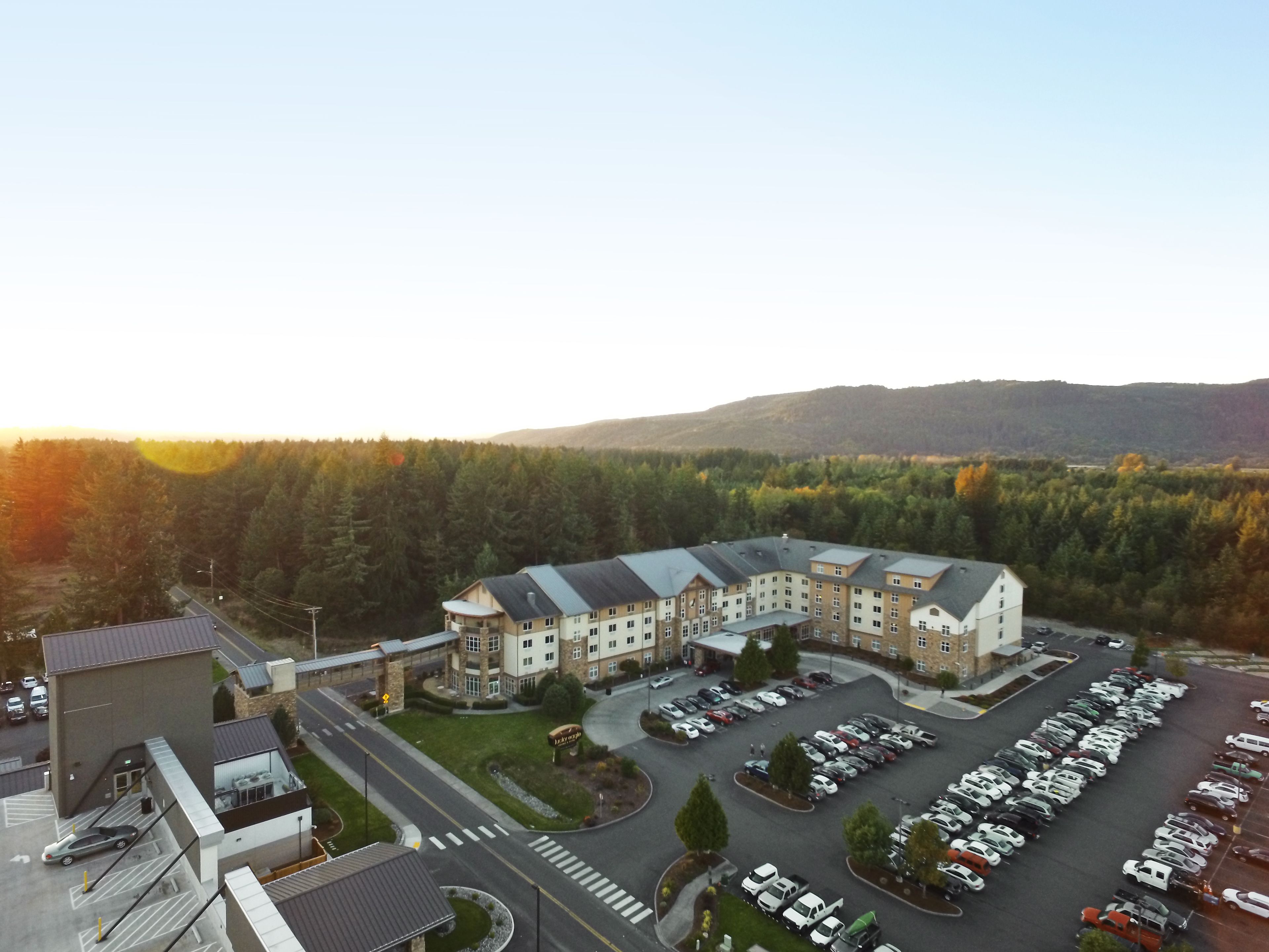 Hotel de vários andares com estacionamento e vista para uma área arborizada.