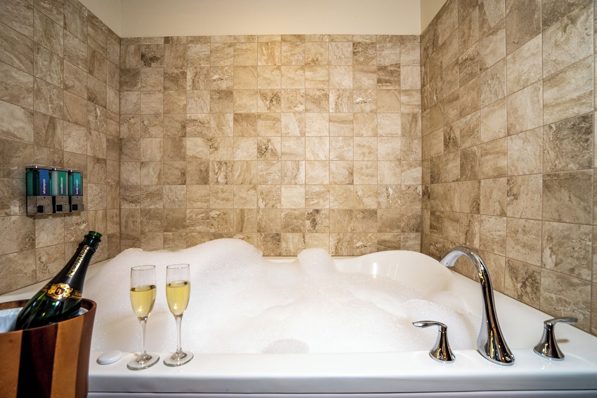 Una bañera con champán y copas, una botella de champán y un balde de madera.