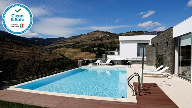 Un área de piscina moderna con una vista despejada del paisaje circundante, que incluye colinas y un cielo claro.