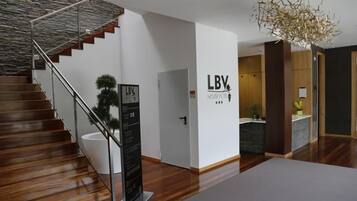 Un interior de hotel moderno con una escalera de madera, una pared de piedra y un letrero para LBV House Hotel.