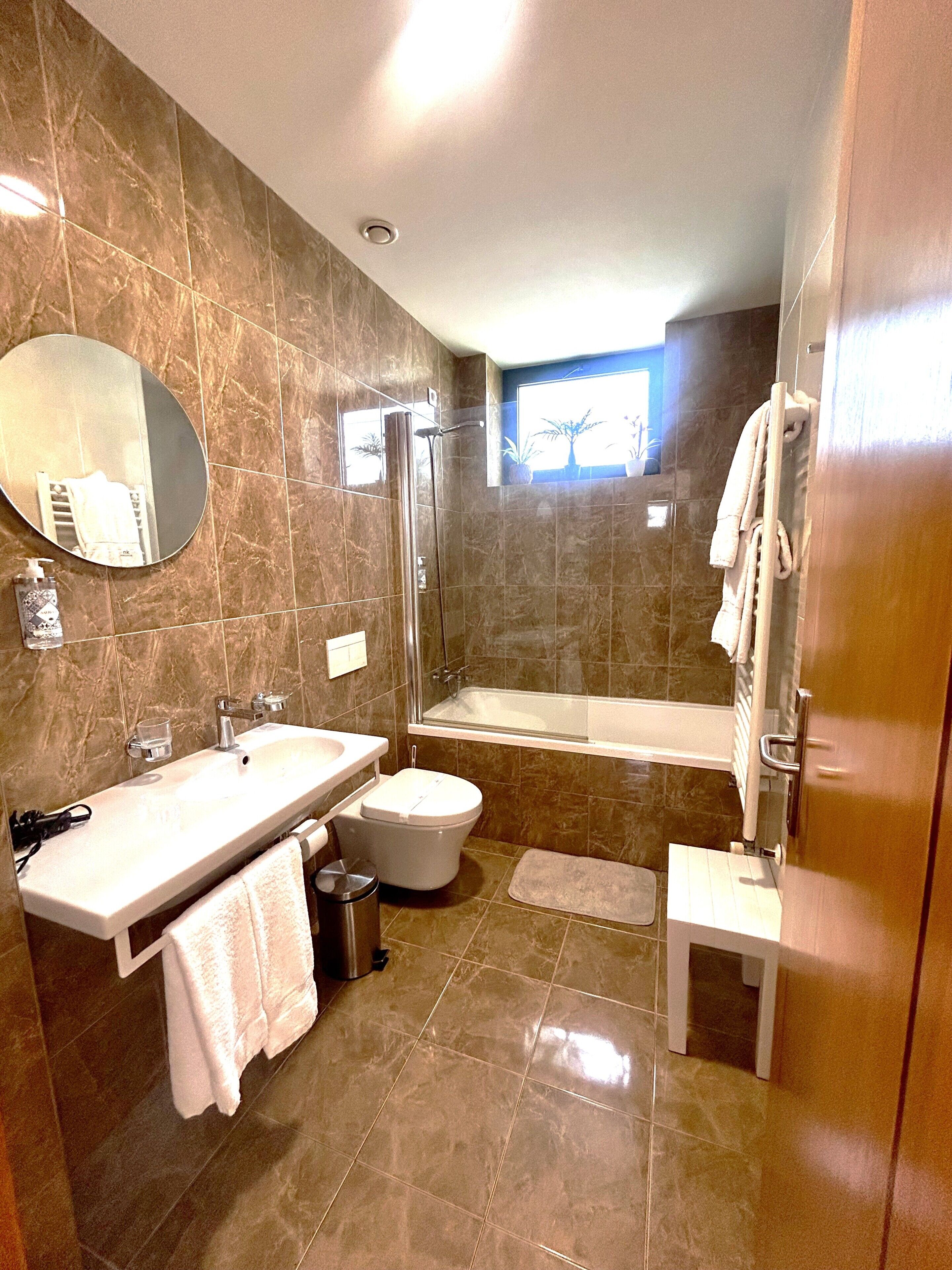 A modern bathroom with a sink, toilet, bathtub, and a shower stall.