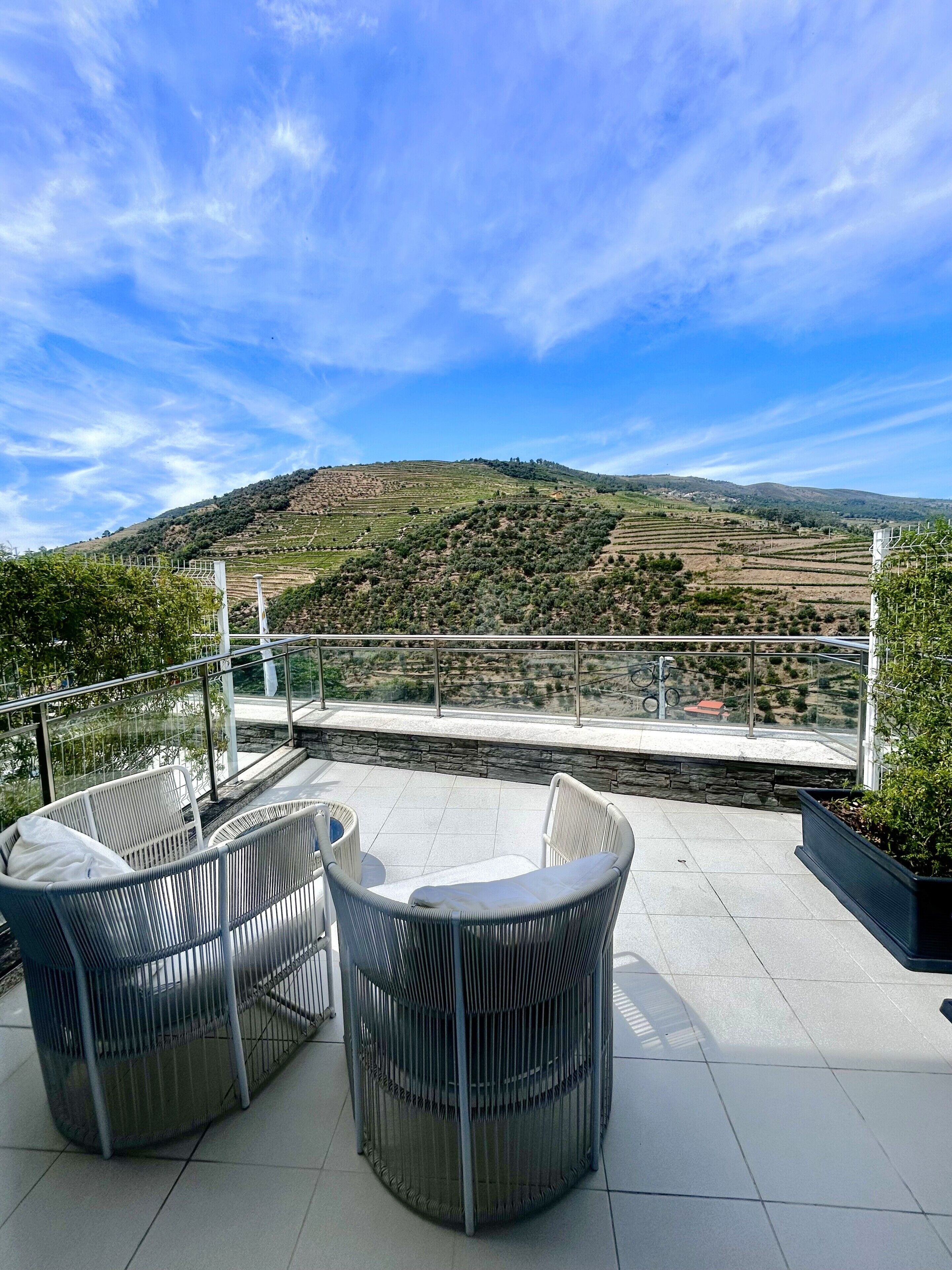 Eine Terrasse mit Korbmöbeln und Blick auf terrassenförmig angelegte Felder.