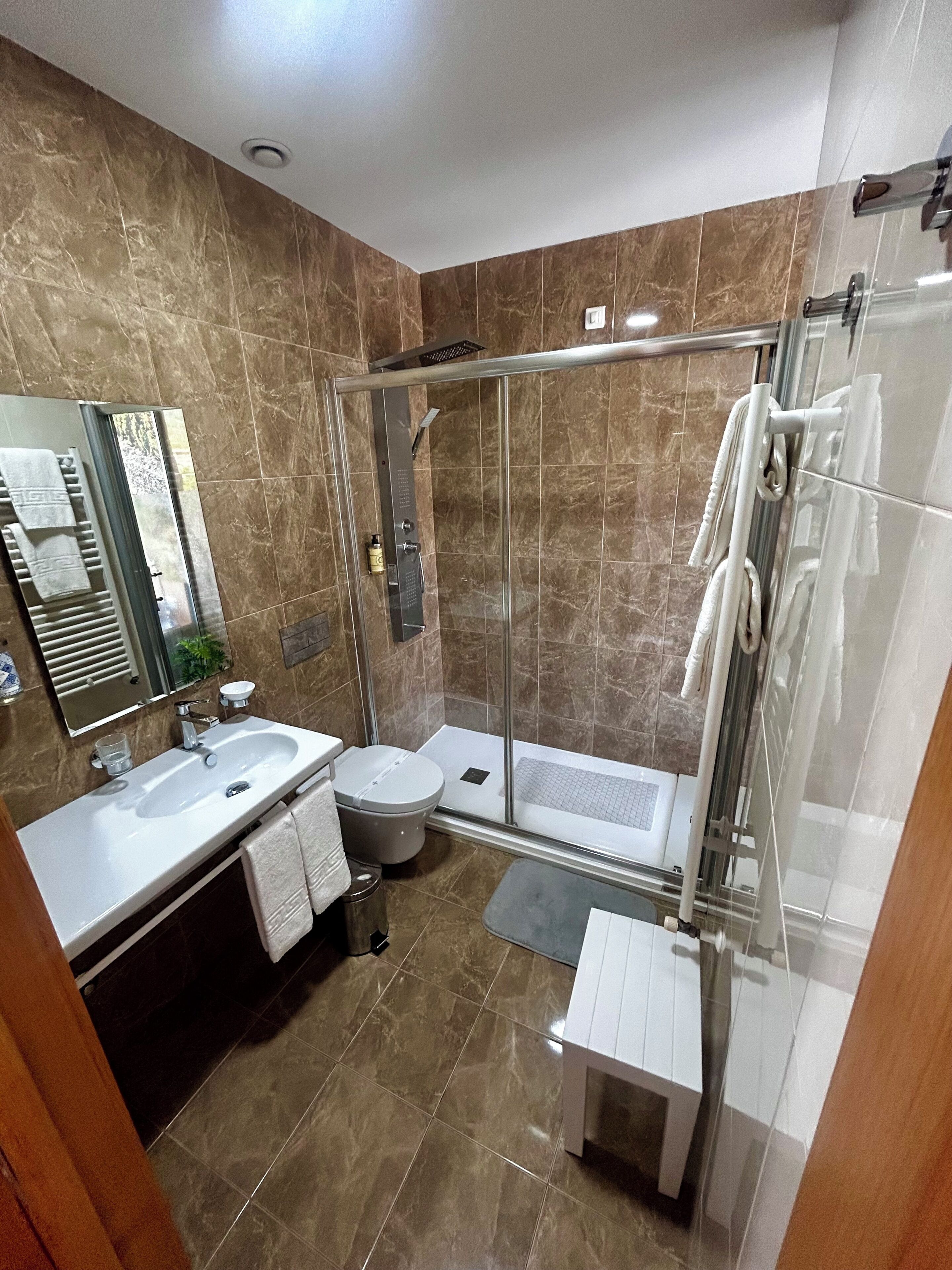 Un bagno moderno con cabina doccia in vetro, un lavandino e un water.