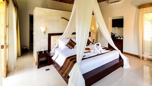 Een ruime slaapkamer met een groot bed, nachtkastje en hemelbed.
