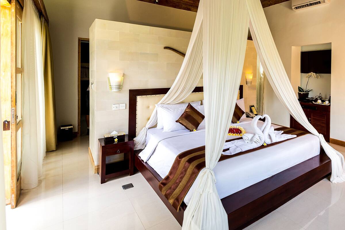 Une chambre spacieuse avec un grand lit, une table de chevet, une commode et un lit à baldaquin.