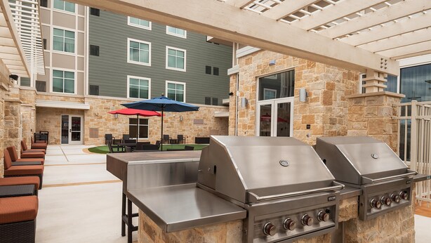 Une terrasse extérieure avec des murs en pierre, un espace barbecue et des sièges.