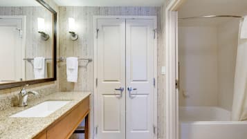 A bathroom with a double vanity, a large mirror, and a shower area.