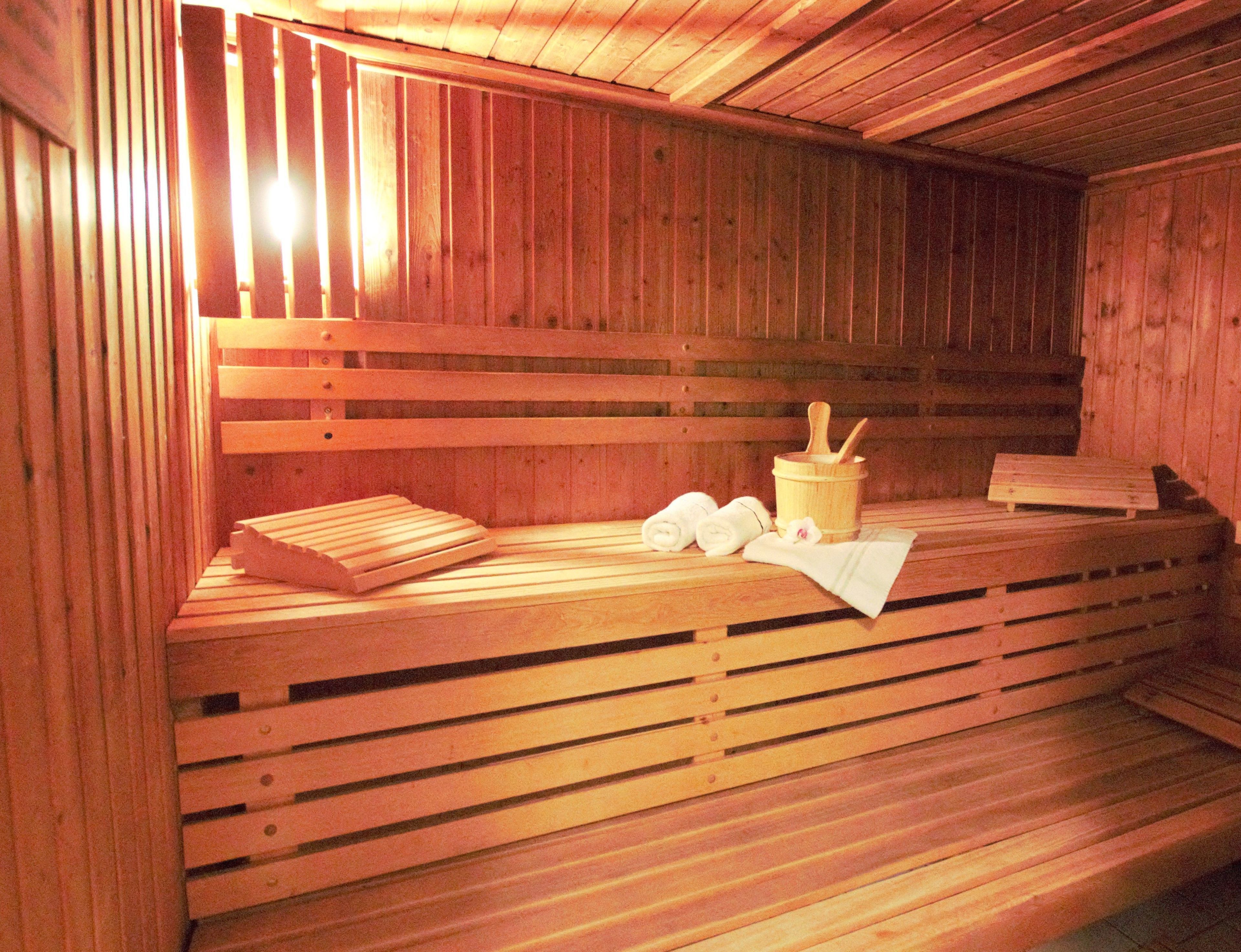 A wooden sauna with benches, towels, and a wooden bucket.