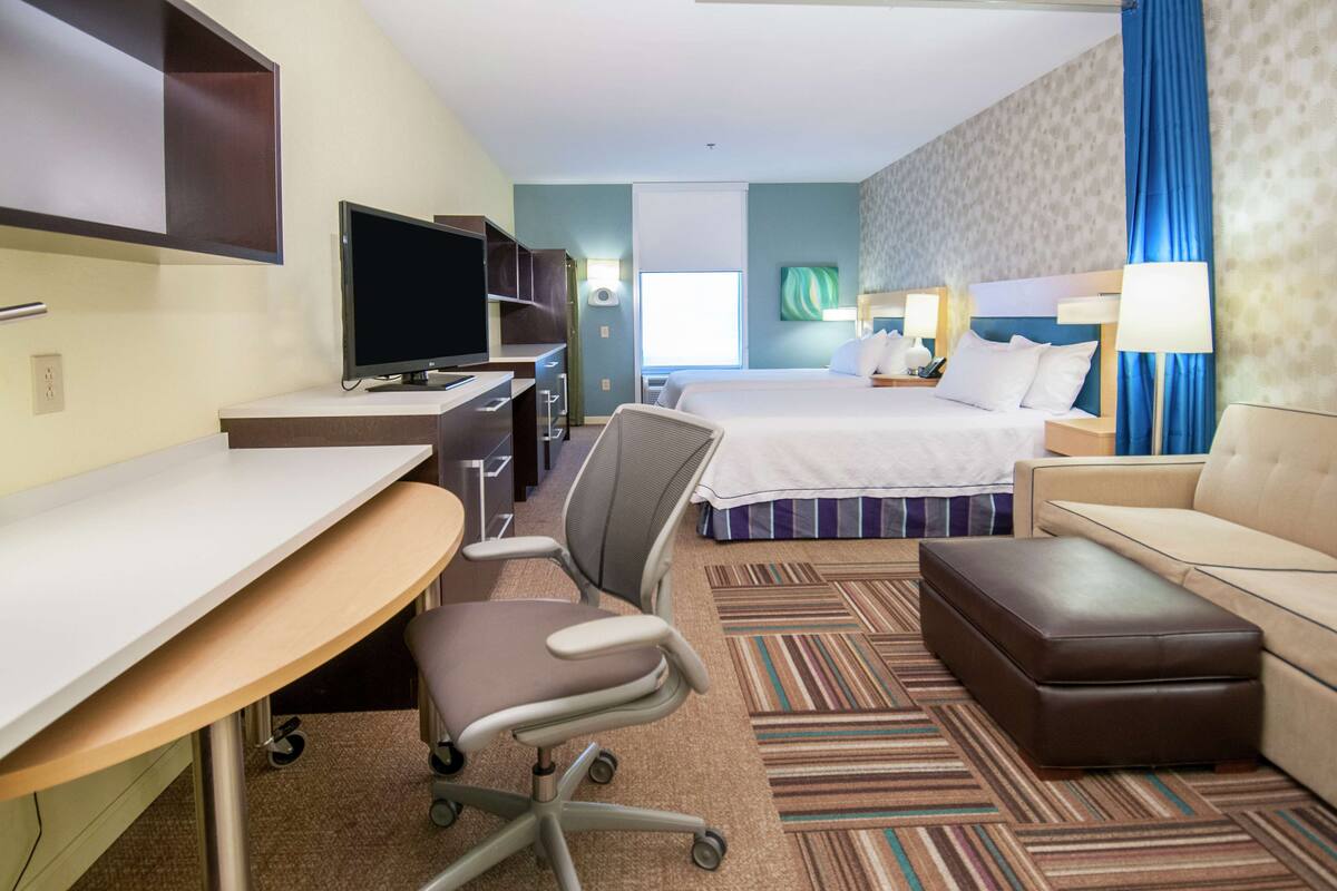 Une chambre d’hôtel équipée d’un bureau, d’une chaise, d’un lit et d’un canapé.