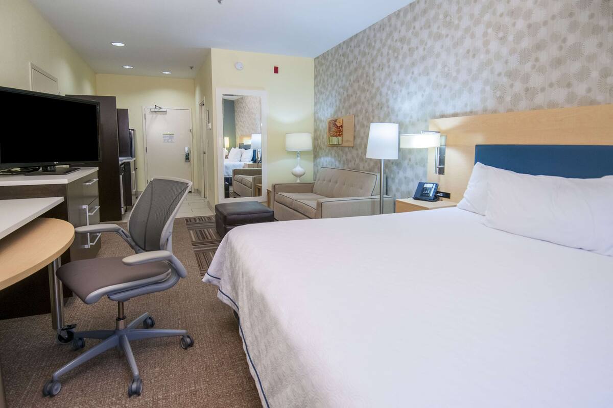 Une chambre d’hôtel équipée d’un lit, d’un bureau, d’une chaise, d’une télévision et de lampes.