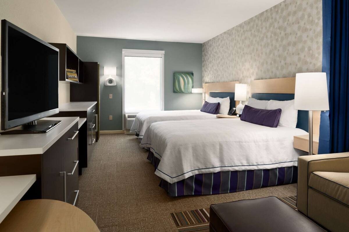 Une chambre d’hôtel équipée d’une télévision, de deux lits, d’un bureau et d’une fenêtre.
