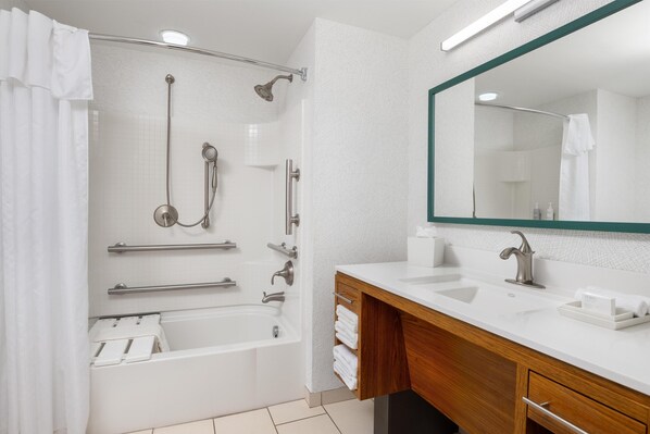 Une salle de bain moderne équipée d’une baignoire, d’une douche et d’un meuble-lavabo avec un miroir.