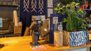 Un espace d’accueil avec un comptoir en bois, une horloge, un panneau indiquant des « conseils » et un mur décoratif orné de motifs de poissons.