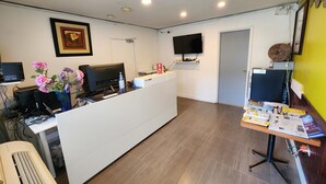 Un espace d’accueil comprenant un bureau, un ordinateur et un téléviseur à écran plat fixé au mur.