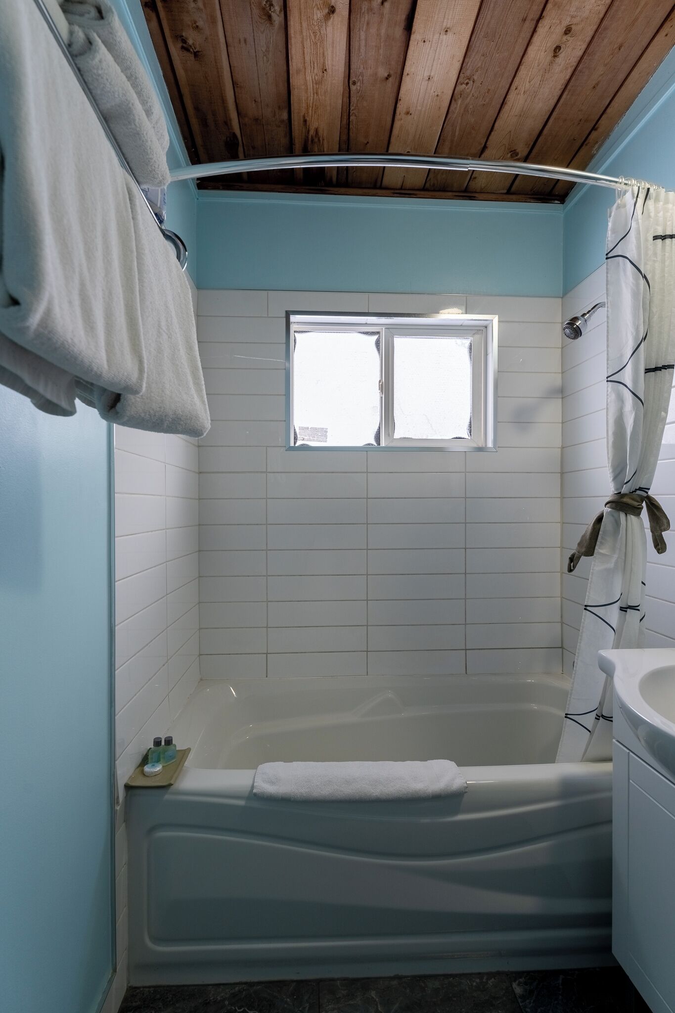 A bathroom with a bathtub, a window, and a shower curtain.