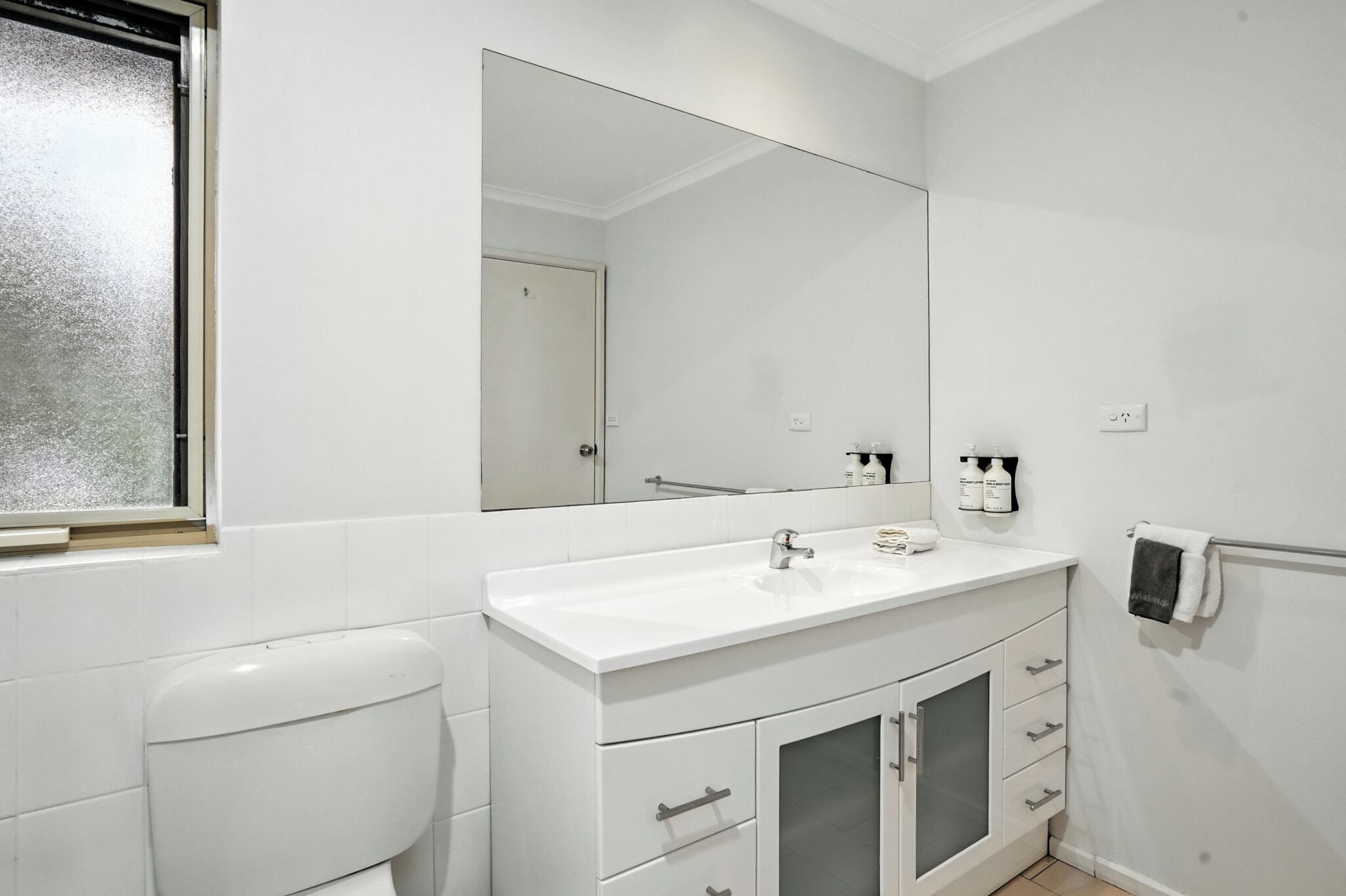 Un baño moderno con lavabo, espejo y retrete blancos.