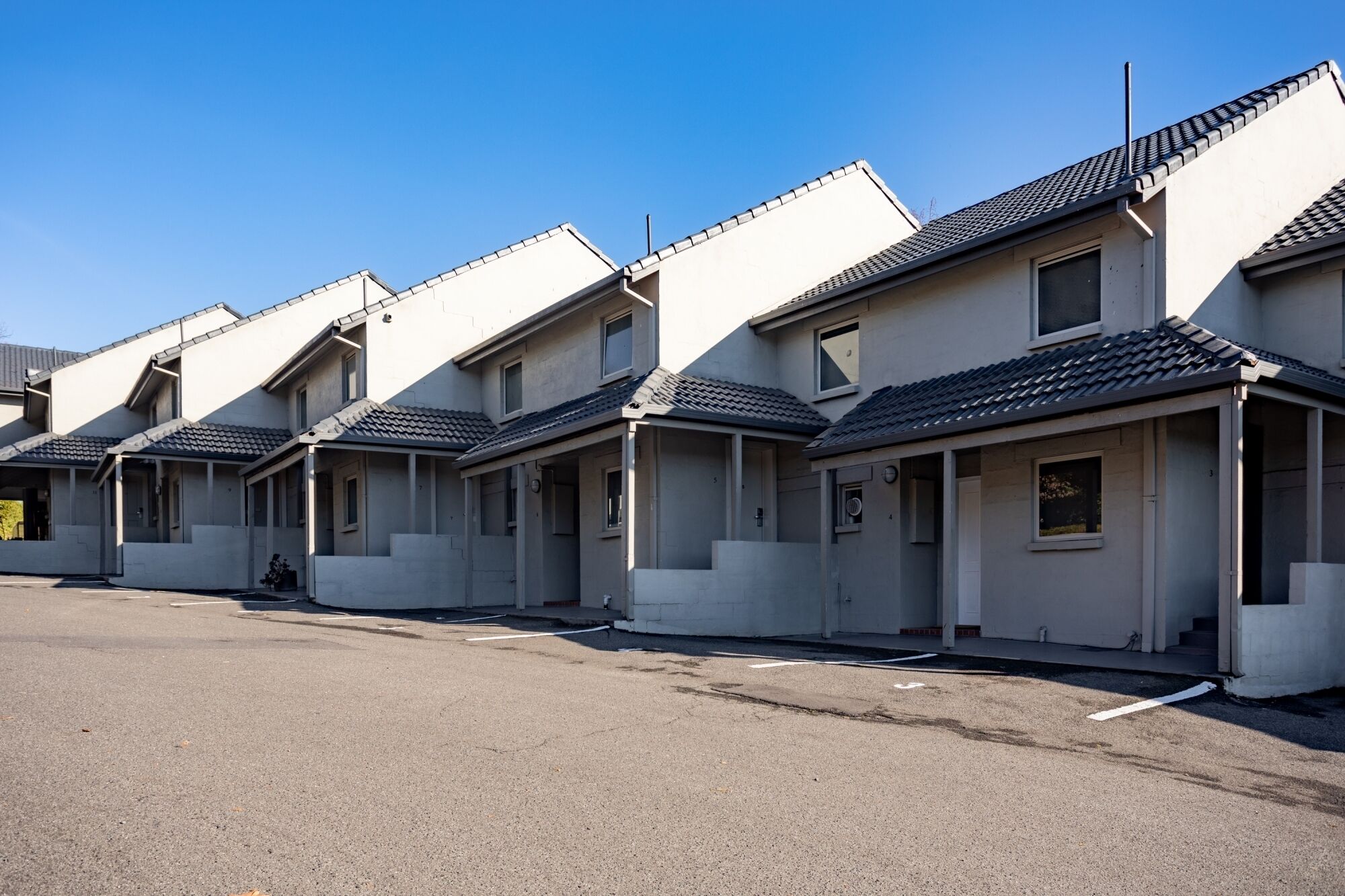 A row of modern, single-story houses with flat roofs and large windows, likely residential units.