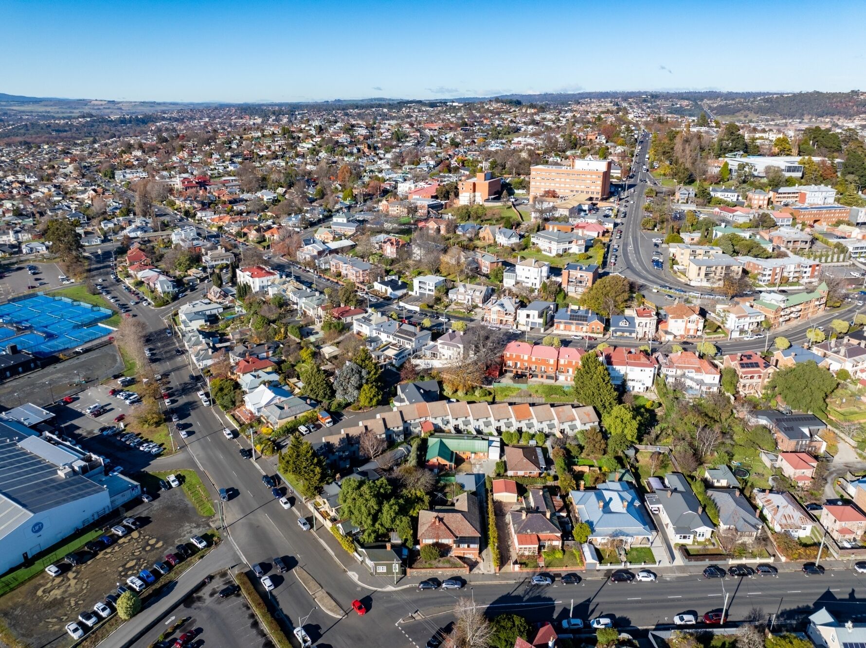Vista aérea de uma área residencial com casas, ruas e um amplo estacionamento.