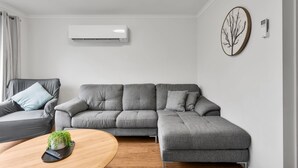 A modern living room with a grey sectional sofa, a wooden coffee table, and a small plant. - Elphin Motel & Serviced Apartments (Launceston)