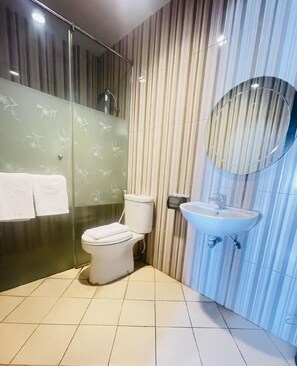 A modern bathroom with a toilet, a sink, and a shower area. - Grand Darussalam Syariah Hotel (Medan)