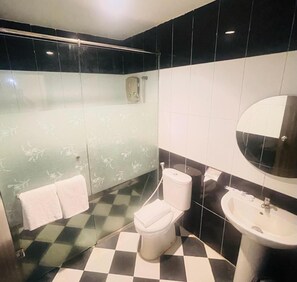A bathroom with a toilet, sink, and a mirror. - Grand Darussalam Syariah Hotel (Medan)