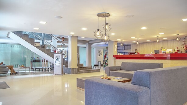 A modern hotel lobby with a reception desk, seating areas, and a staircase. - Hotel El Portón de San Joaquín (Medellín)