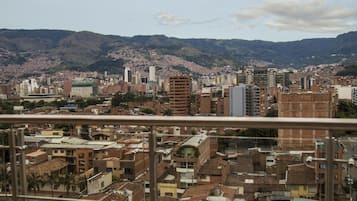 A cityscape with a mix of modern and traditional buildings, a prominent hill in the background, and a clear sky.