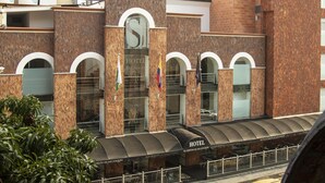 A hotel with a modern brick facade, arched windows, and a sign indicating it is located in the Port of San Joaquin. - Hotel El Portón de San Joaquín (Medellín)