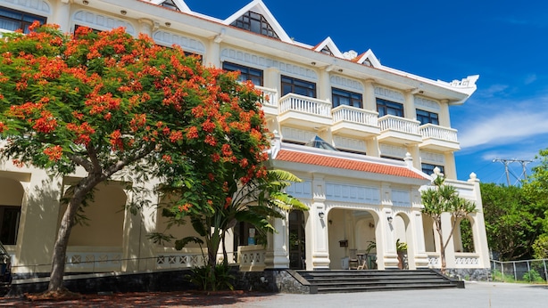 A large, white colonial-style building with multiple balconies and a red-tiled roof.