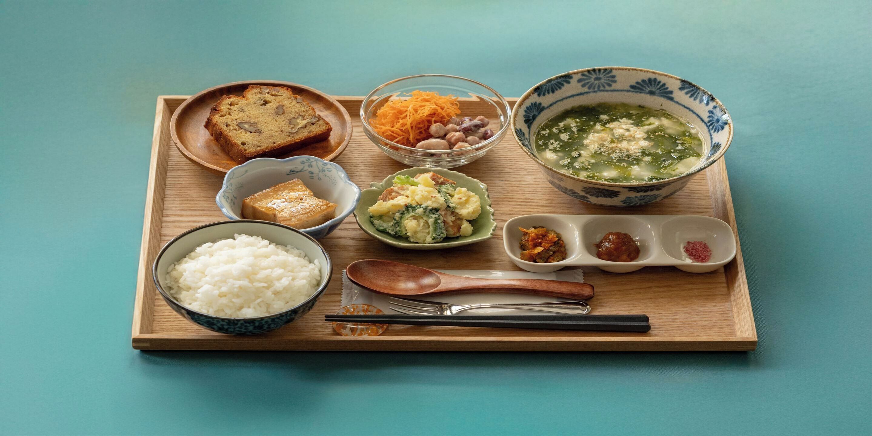 A wooden tray with various Japanese dishes including rice, soup, and pickled vegetables.